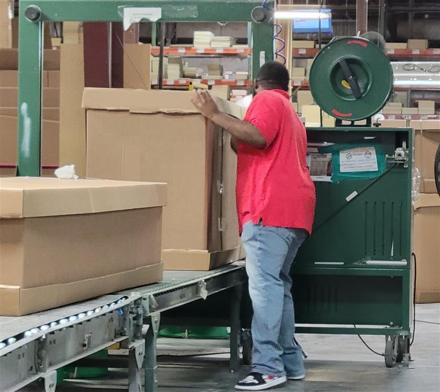 Derickko Sims straightens a box on an assembly line.